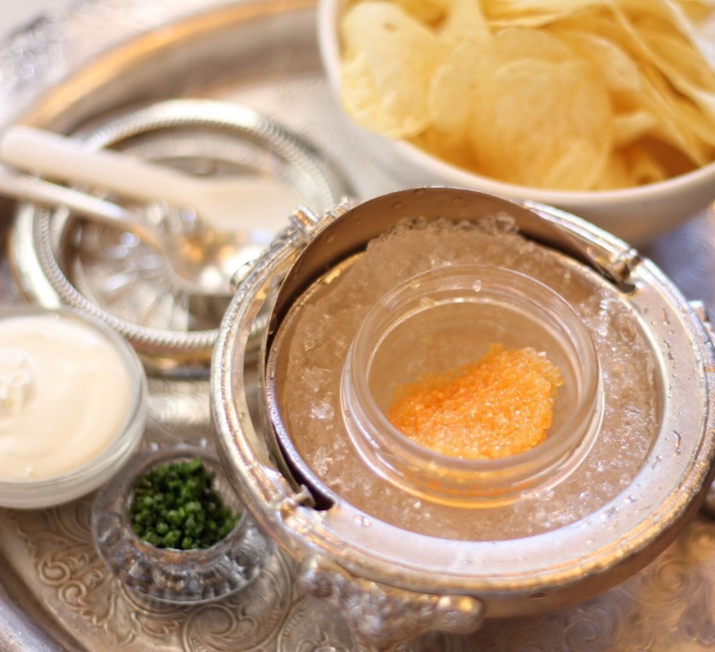 Caviar and chips on a silver serving tray.
