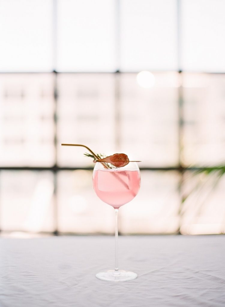 A pink gin and tonic garnished with a fig.
