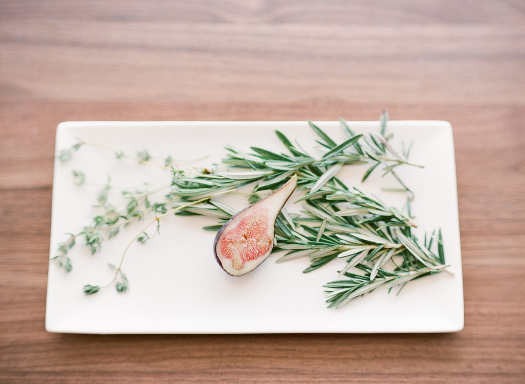 A plate with fig, rosemary and thyme.