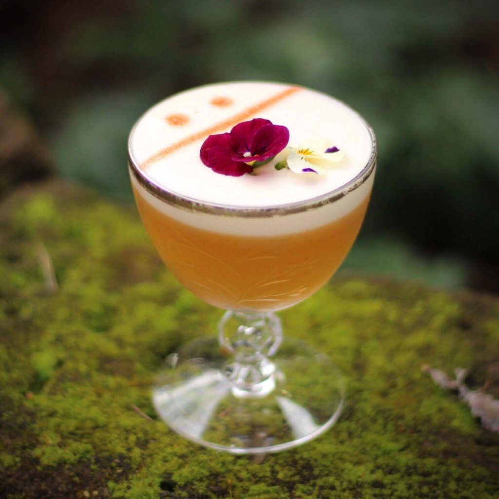 Cocktail with ornate floral garnish on foam.
