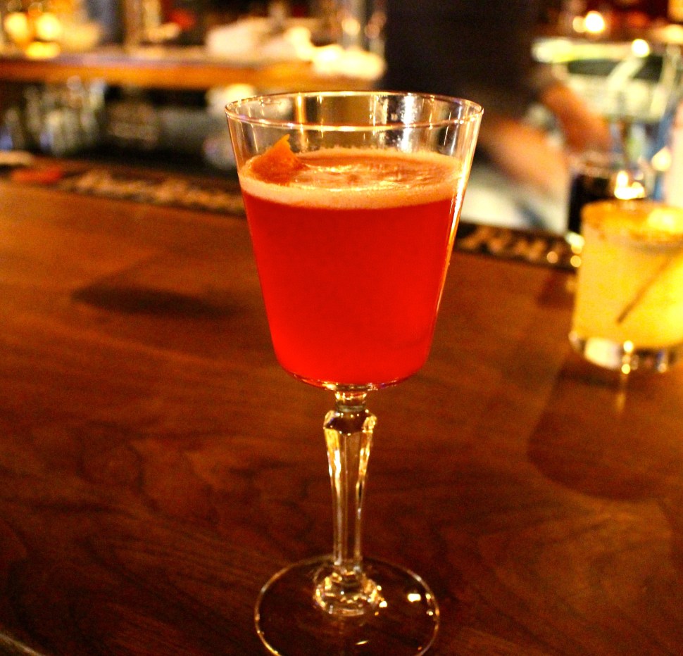 Bright red cocktail on a bar.